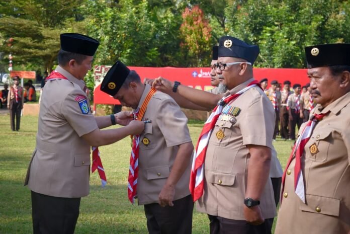 Gubernur NTB H. Lalu Muhamad Iqbal menyerahkan penghargaan pada Ketua Kwarda Pramuka NTB H. Fathul Gani pada Peringatan HUT ke-64 Pramuka di Lapangan Brida NTB, Sabtu, 16 Agustus 2025. (Suara NTB/ist)