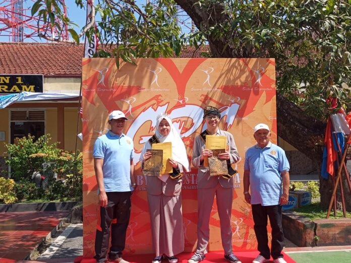 Kepala Sekolah SMAN 1 Mataram, Burhanudin (kiri) saat memberikan penghargaan berupa piagam kepada King and Queen Smansa ditemani Ketua Komite Sekolah (kanan) di lapangan sekolah pada Sabtu, 16 Agustus 2025. (suarantb.com/sib)